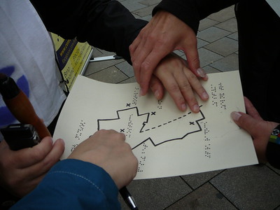 Fotografie nevidomého prohlížejícího si soutěžní mapu v bodovém písmu